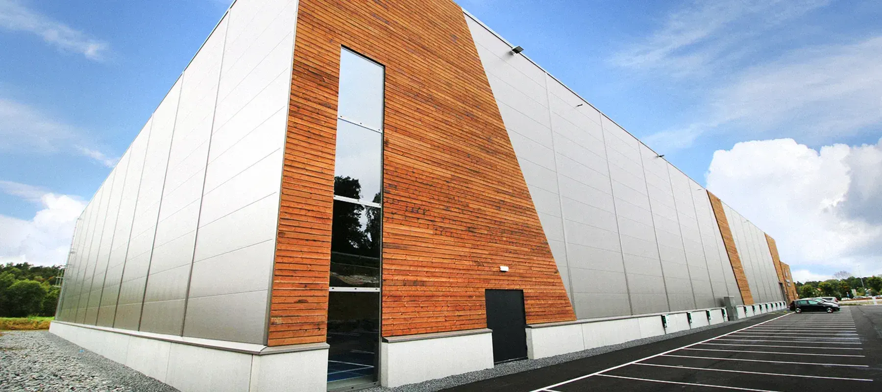 Campus Grimstad Arena, en lang hall med fasade i aluminium og tre